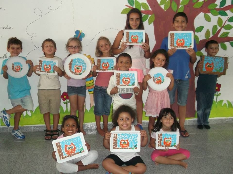Crianças a mostrar trabalhos de mosaico com corujas feitos no workshop